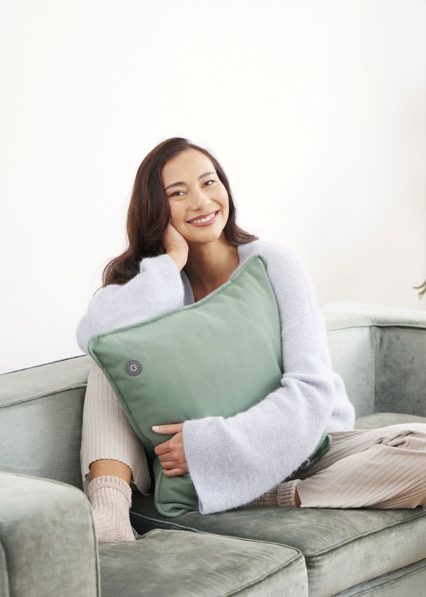 Woman hugging a green medisana heated pad and enjoying its gentle warmth.
